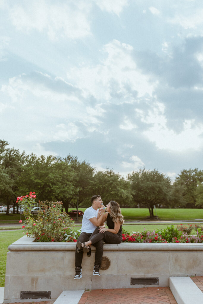 Couple sitting down at a park eating ice cream during a summer photoshoot 