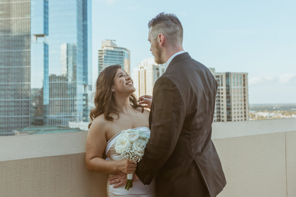 Couple looking at each other, skyline in the background, during their Houston elopement.