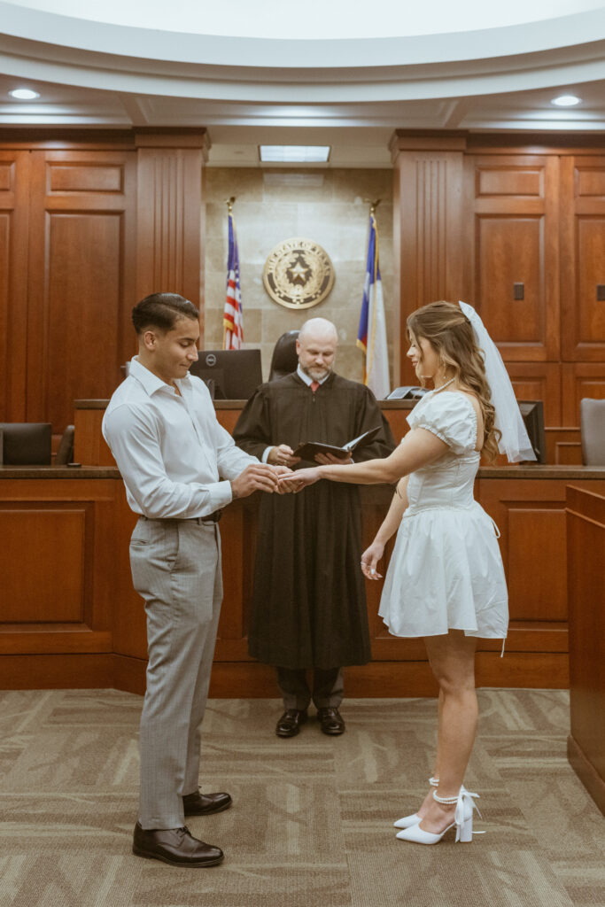 Couple exchanging rings inside a courtroom.