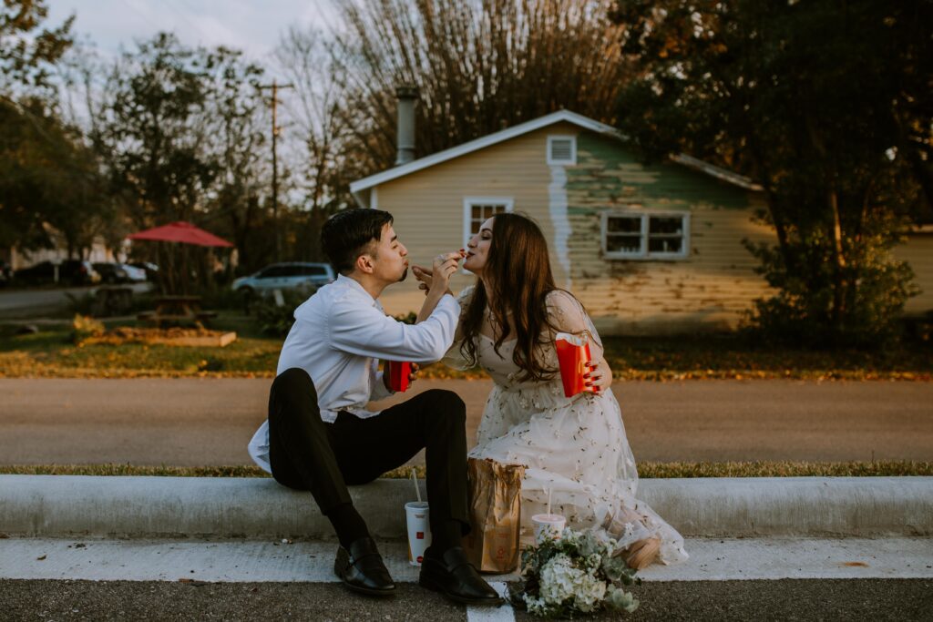 Couple sitting on the sidewalk, eating, during their Houston elopement.
