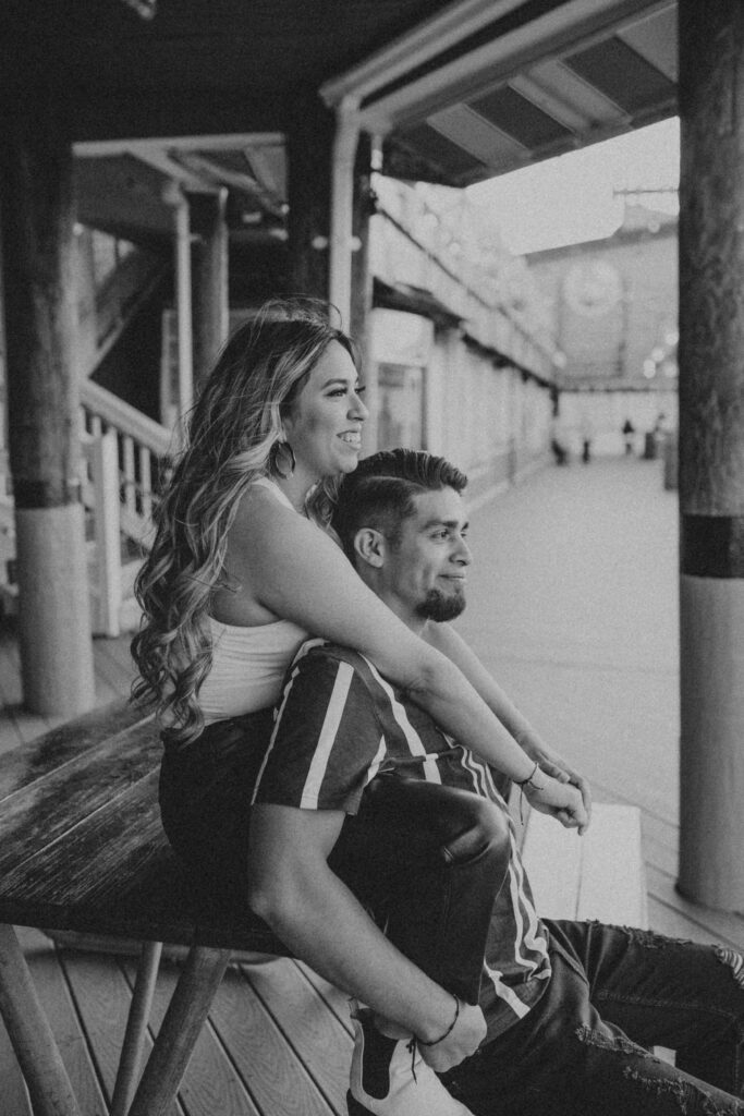 Husband and wife sitting on a picnic table during a summer photoshoot.
