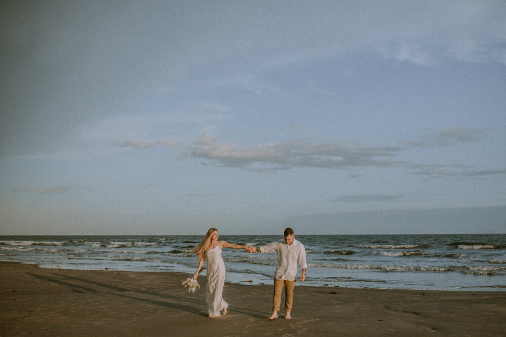 Couple walking down the beach with waves in the background during their elopement.