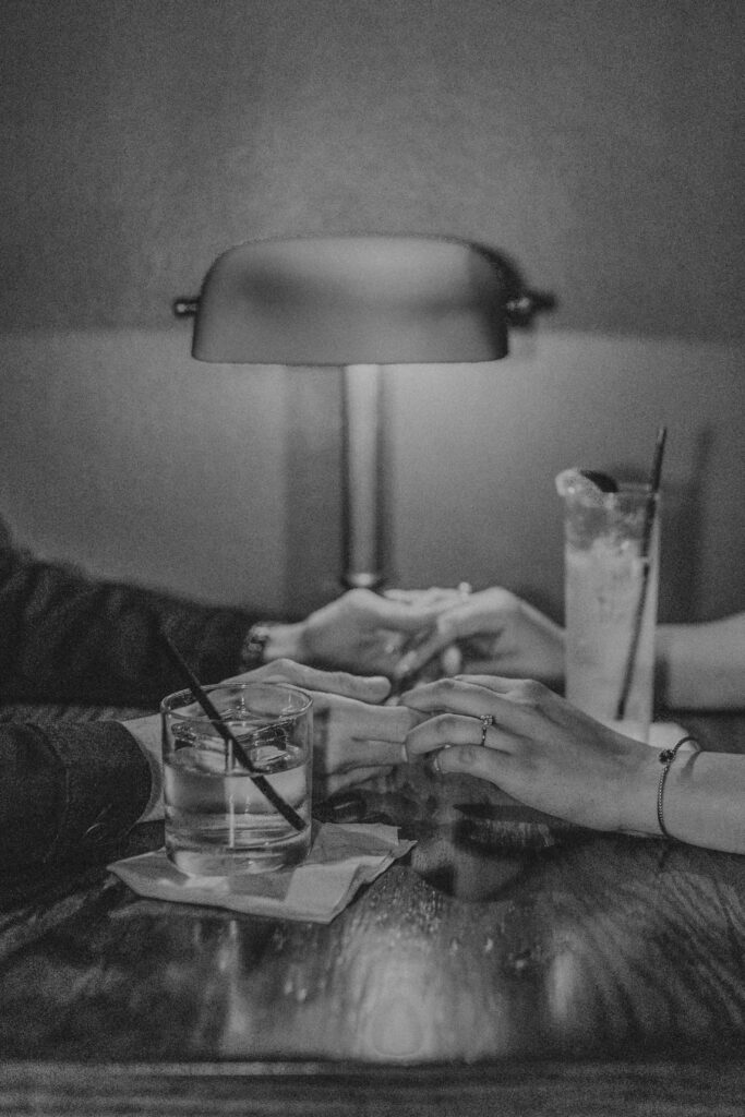 Couple holding hands and drinks are on the table 