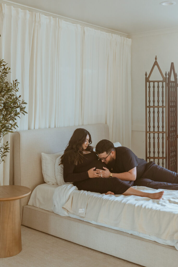 Couple on the bed for their maternity photoshoot.