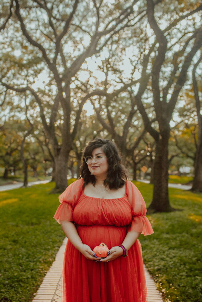 Fall maternity photoshoot and holding a small pumpkin.