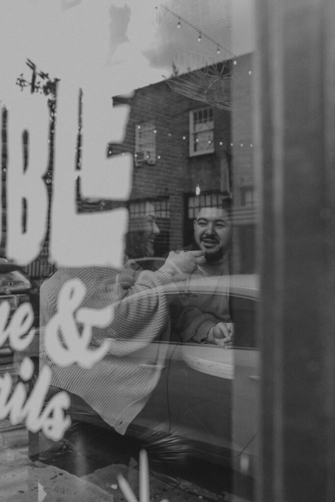 Couple sitting at a table seeing them through a window.