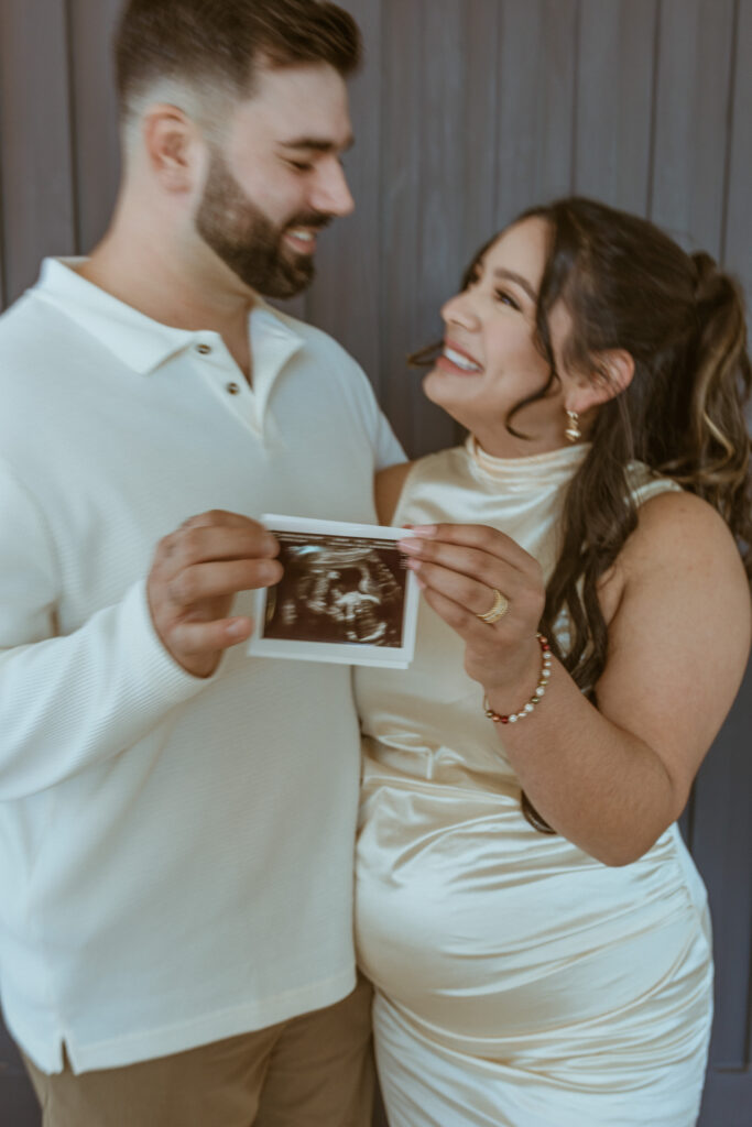 Couple holding baby's ultrasound during their maternity photoshoot