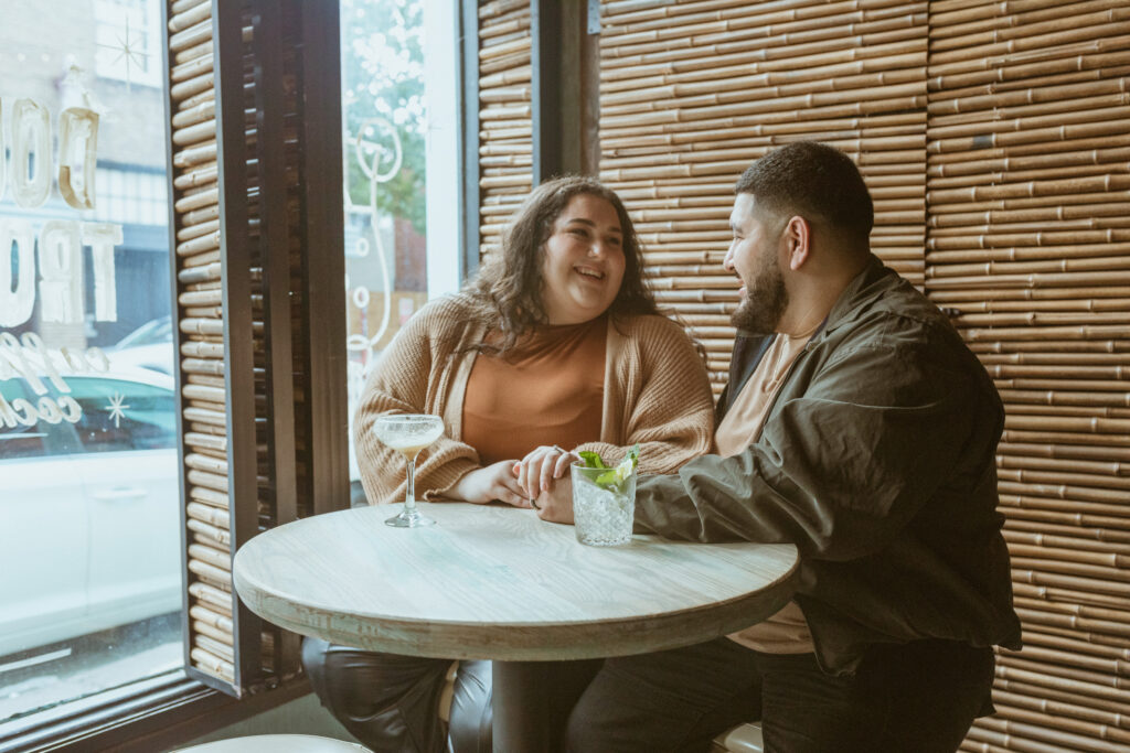 Couple laughing sitting at a table during their 1st Year Anniversary Photoshoot 