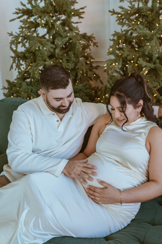 Couple siting down on a couch during a winter maternity photoshoot