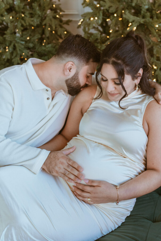 Couple sitting down on a couch during their maternity photoshoot