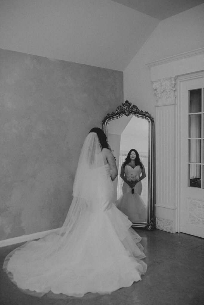 bride standing in front a mirror for her wedding photos inside the Oak Atelier.