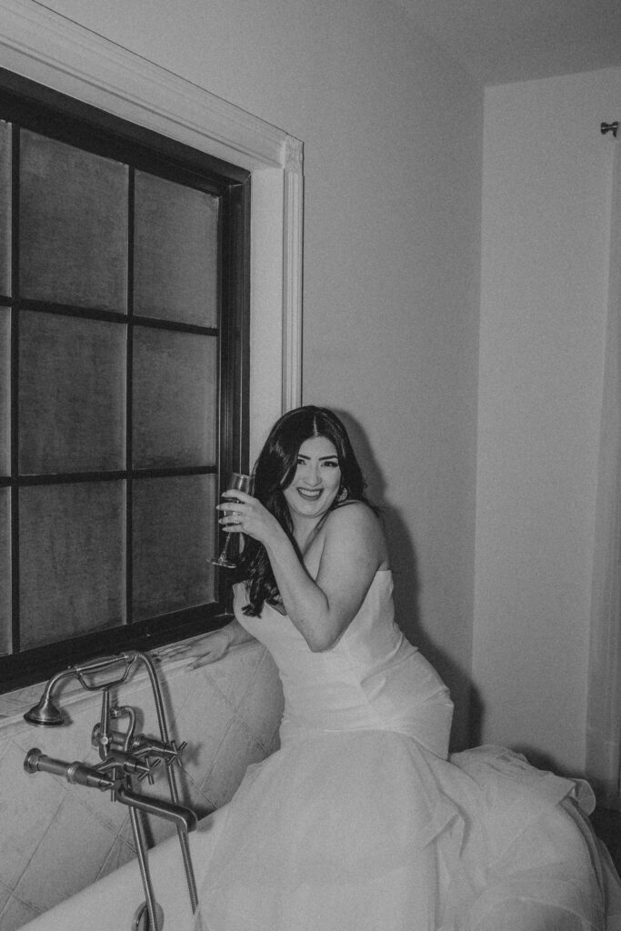 Bride taking photos inside a bathtub during her wedding ceremony.