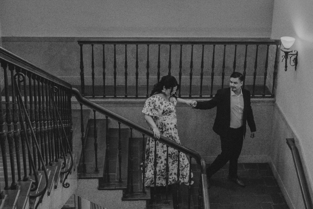 Man leading his fiance down the stairs inside the Julia Ideson Library