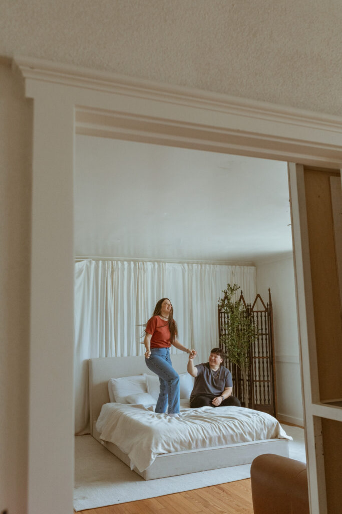 Winter photoshoot of a couple at home, jumping on the bed.