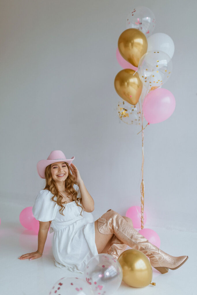 Girl sitting on the floor with a cowgirl hat and balloons