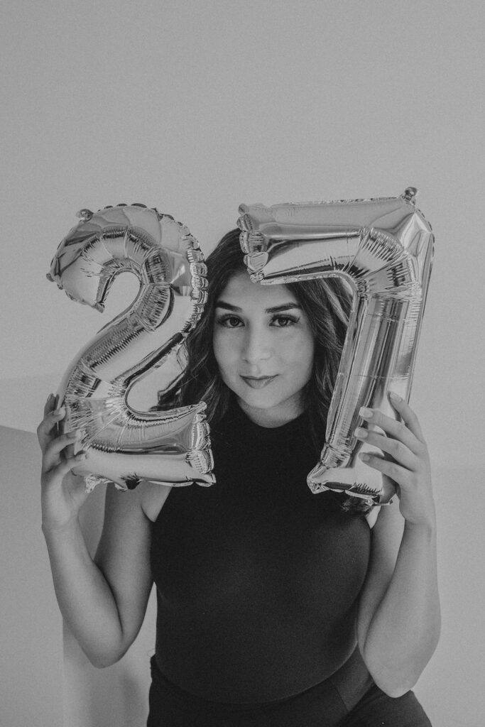 Birthday photoshoot ideas of a girl holding the number 27 balloons