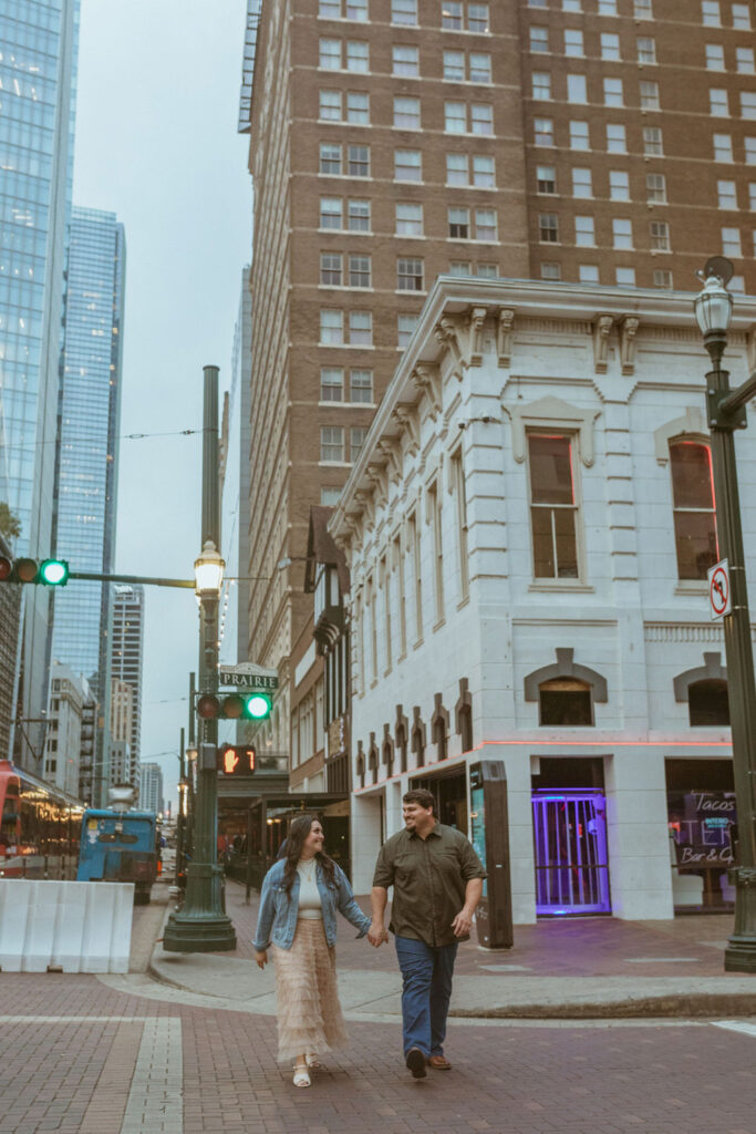Couple holding hands walking through downtown during their fall photoshoot.