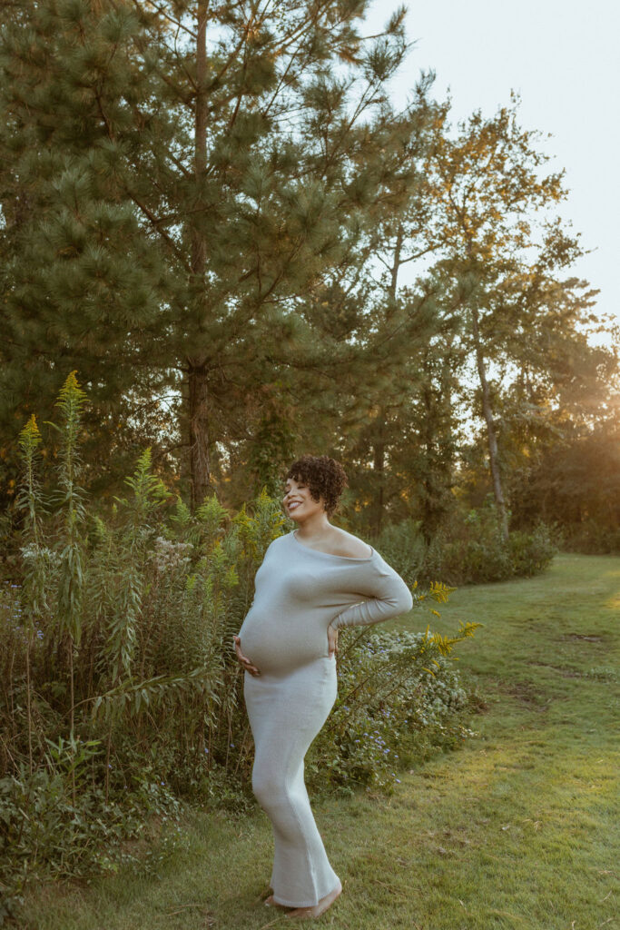 For a fall photoshoot, a pregnant women, standing up, during her Maternity Photoshoot at the park. 
